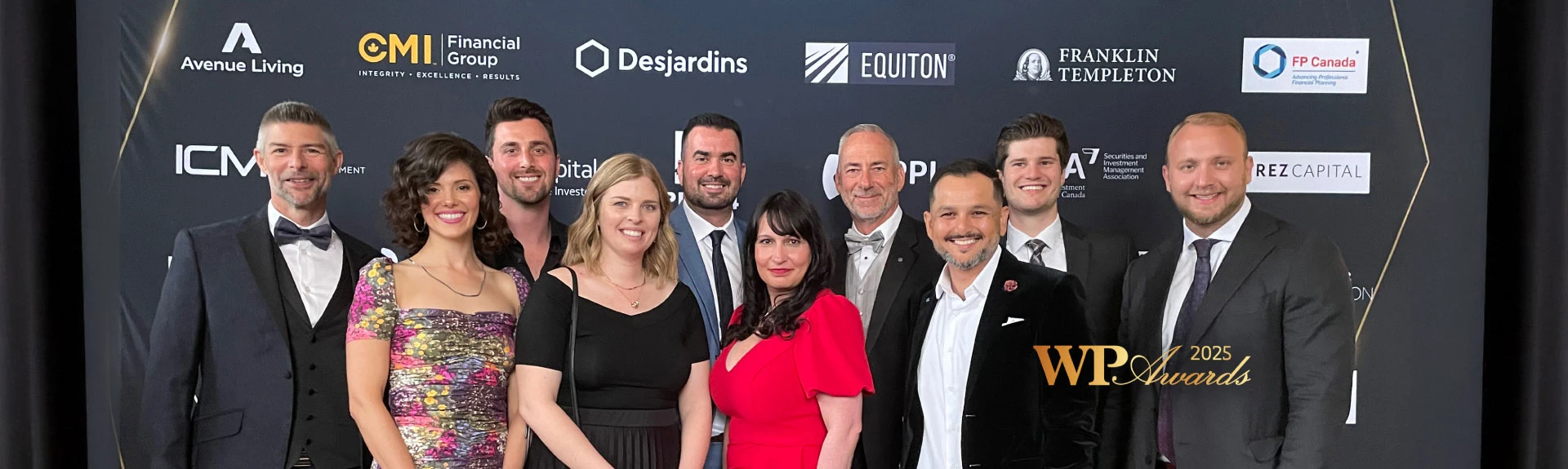 A group of smiling people posing with an award plaque at an awards event.